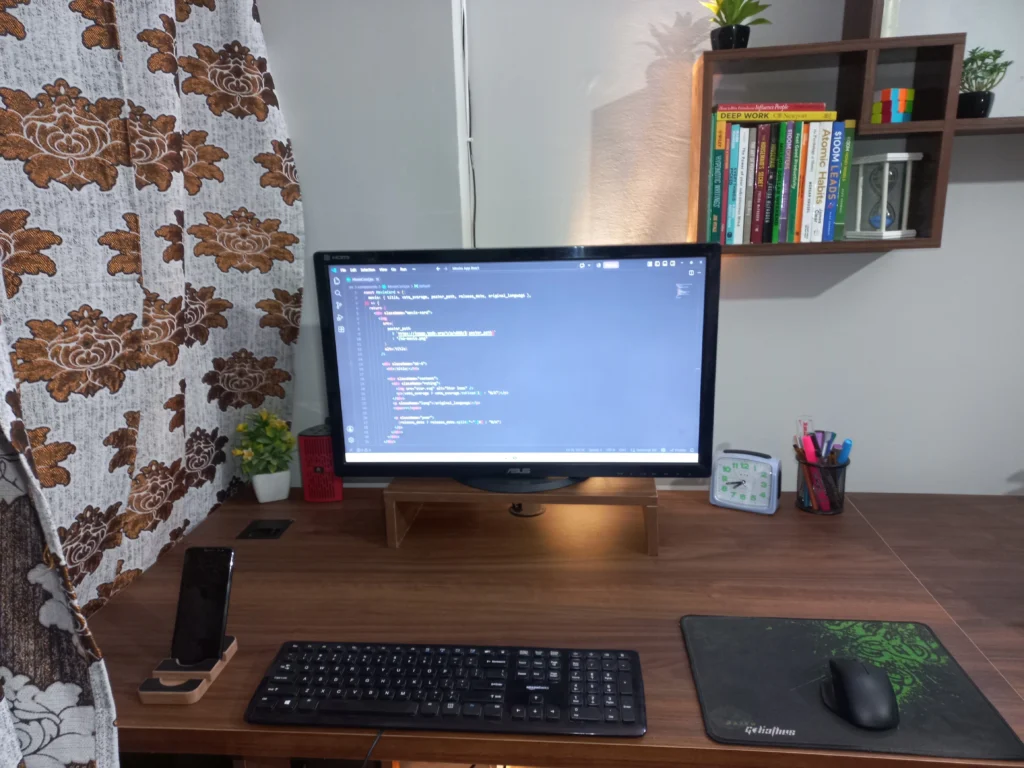 Developer workspace with a monitor showing code for a React project, on a desk with books on productivity and business